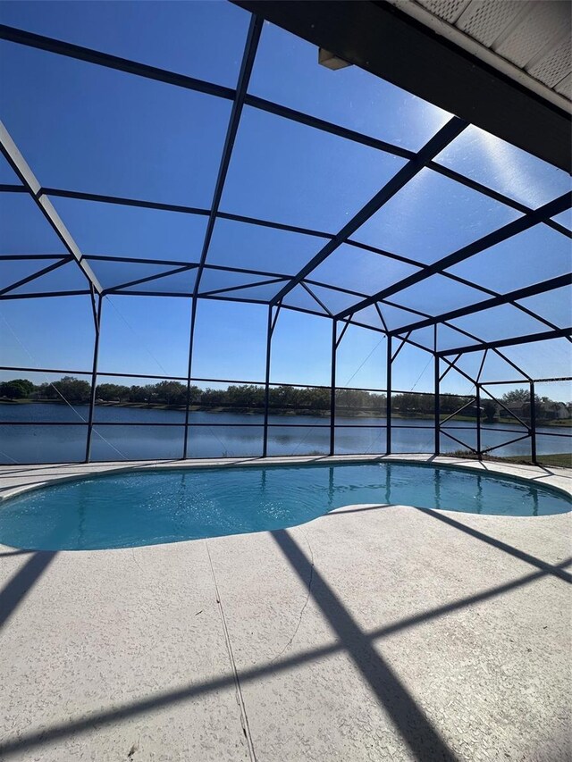 outdoor pool featuring a water view, glass enclosure, and a patio