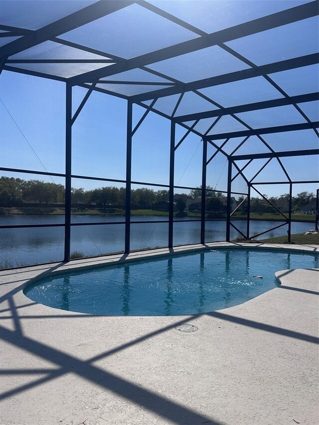 outdoor pool featuring a lanai, a patio area, and a water view