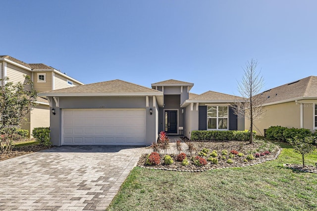 view of front of house featuring a front lawn, decorative driveway, an attached garage, and stucco siding