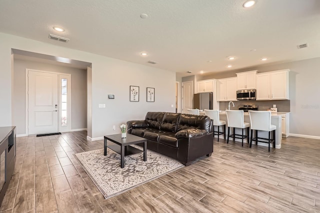 living area featuring baseboards, recessed lighting, visible vents, and wood tiled floor