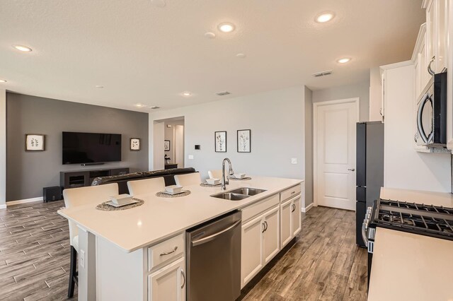 kitchen with a center island with sink, white cabinets, a sink, and stainless steel dishwasher