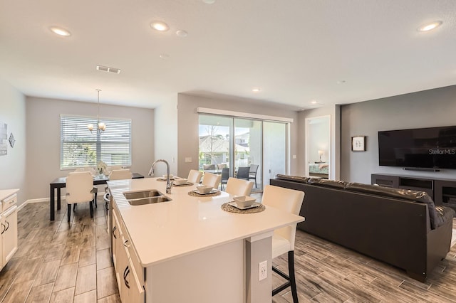 kitchen featuring open floor plan, a breakfast bar, wood finish floors, and a sink