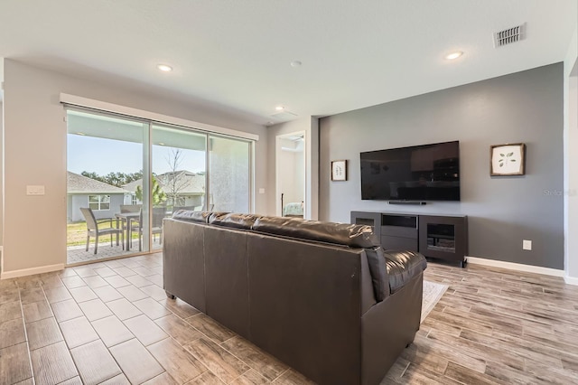 living area with light wood finished floors, recessed lighting, visible vents, and baseboards