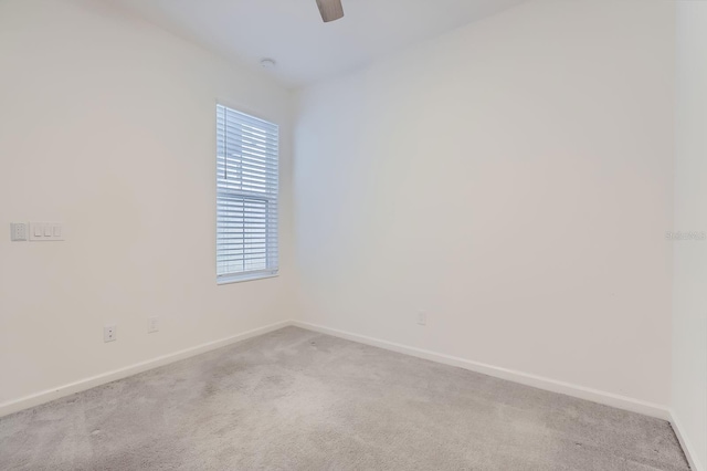 carpeted spare room featuring a ceiling fan and baseboards