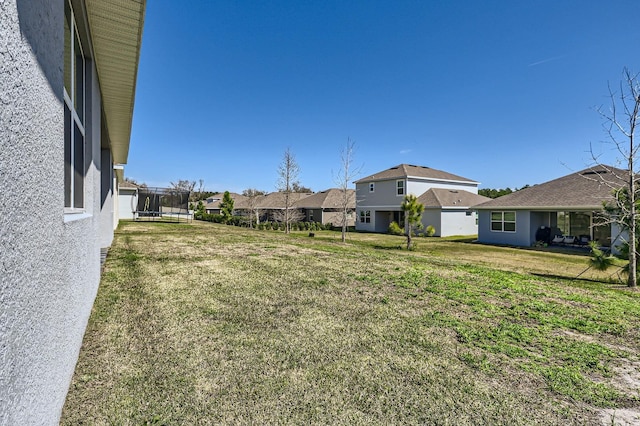 view of yard with a trampoline and a residential view