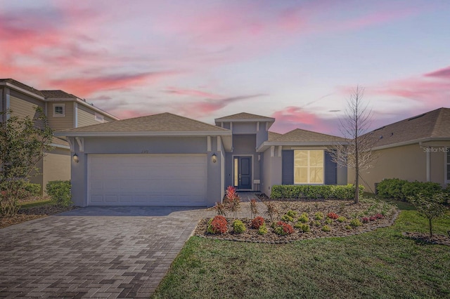 view of front of home featuring a garage, a front yard, decorative driveway, and stucco siding