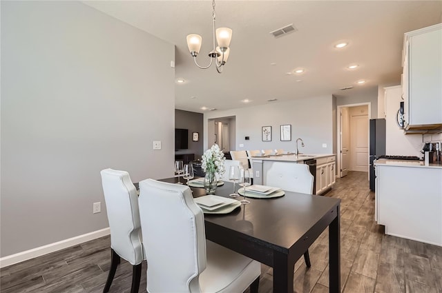 dining area featuring visible vents, a notable chandelier, baseboards, and wood finished floors