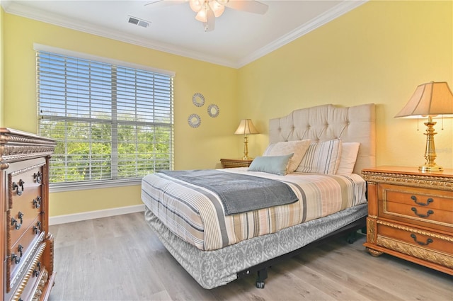 bedroom with ornamental molding, visible vents, baseboards, and wood finished floors