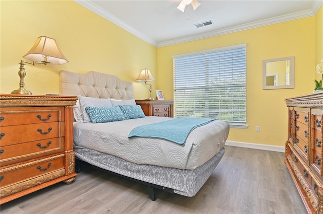 bedroom featuring visible vents, crown molding, and wood finished floors