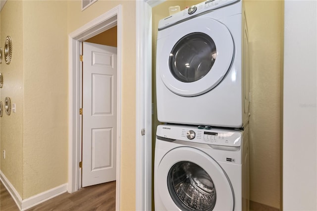 laundry room featuring laundry area, stacked washer / dryer, wood finished floors, visible vents, and baseboards