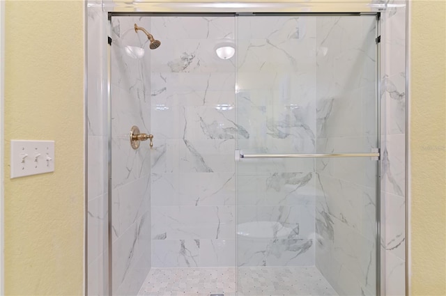 full bath with a marble finish shower and a textured wall