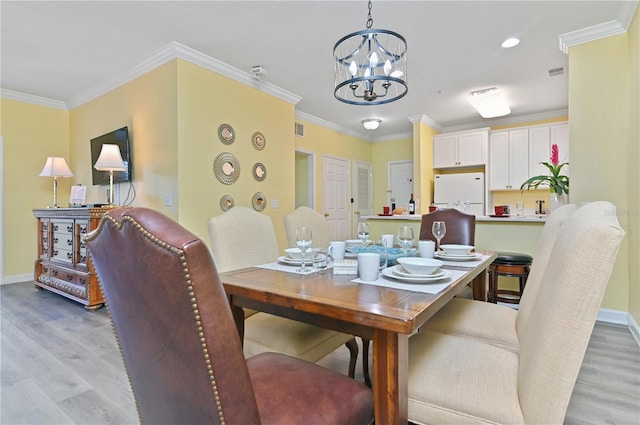 dining room featuring light wood finished floors, baseboards, and ornamental molding