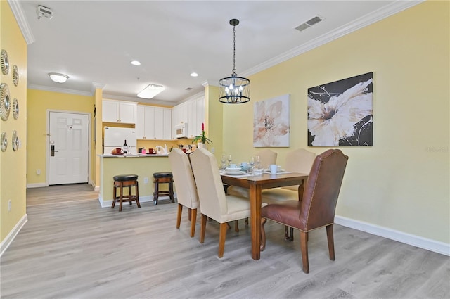 dining room with baseboards, light wood-style floors, and crown molding