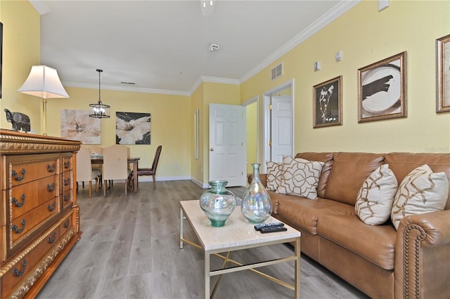 living area featuring ornamental molding, light wood-type flooring, visible vents, and baseboards