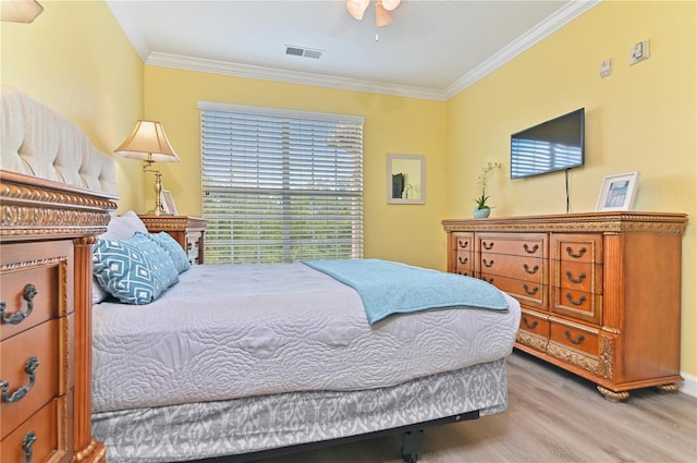 bedroom with ceiling fan, visible vents, crown molding, and wood finished floors