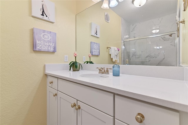 bathroom with a marble finish shower and vanity