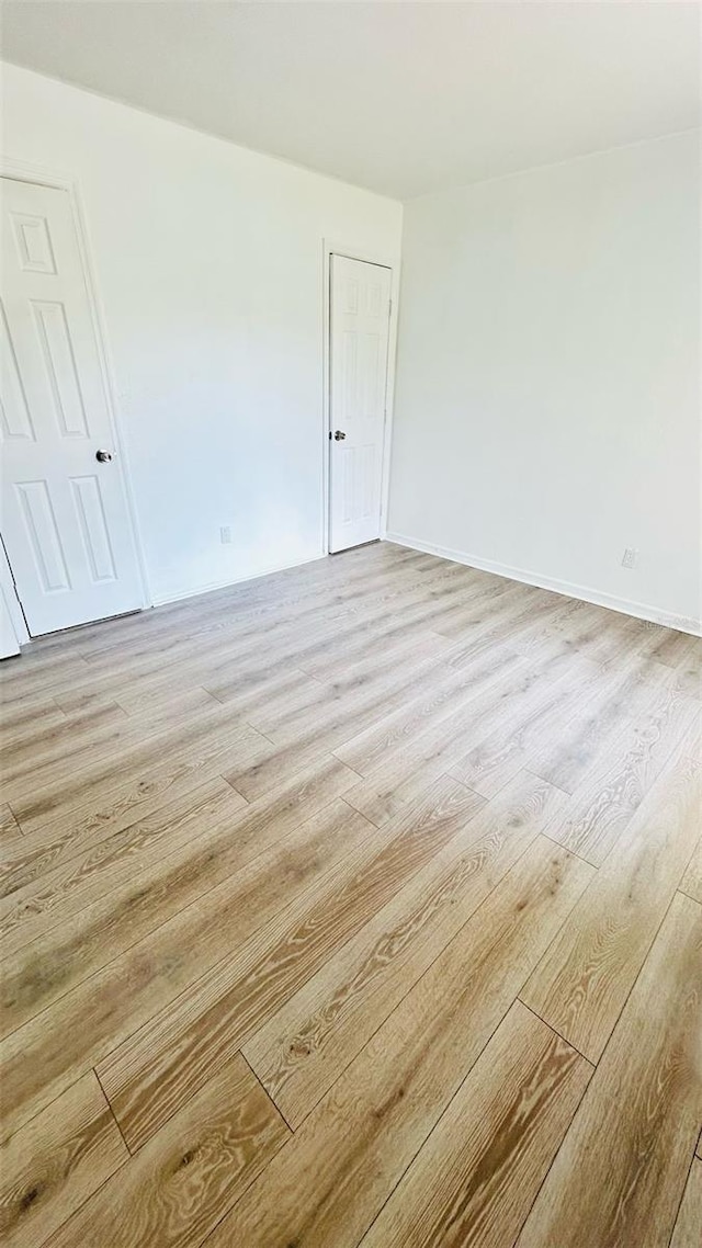 unfurnished room featuring baseboards and light wood finished floors