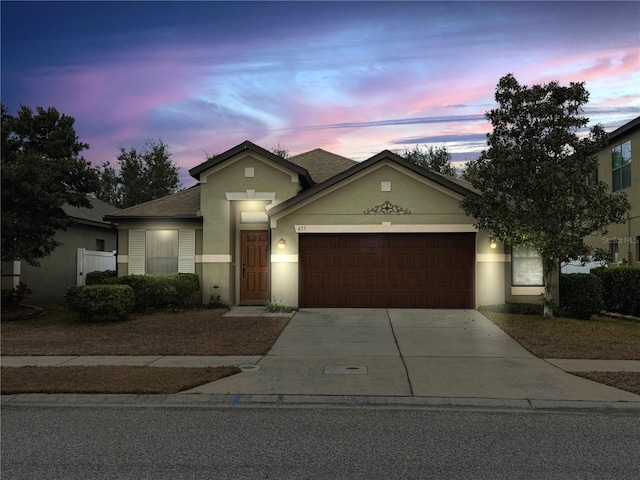 view of front of house featuring a garage, driveway, roof with shingles, and stucco siding