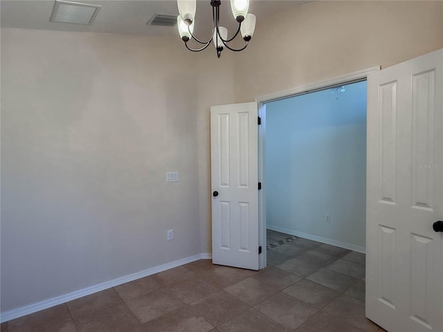 spare room featuring visible vents, a notable chandelier, and baseboards