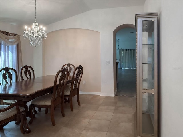 dining space featuring lofted ceiling, light tile patterned floors, arched walkways, baseboards, and an inviting chandelier