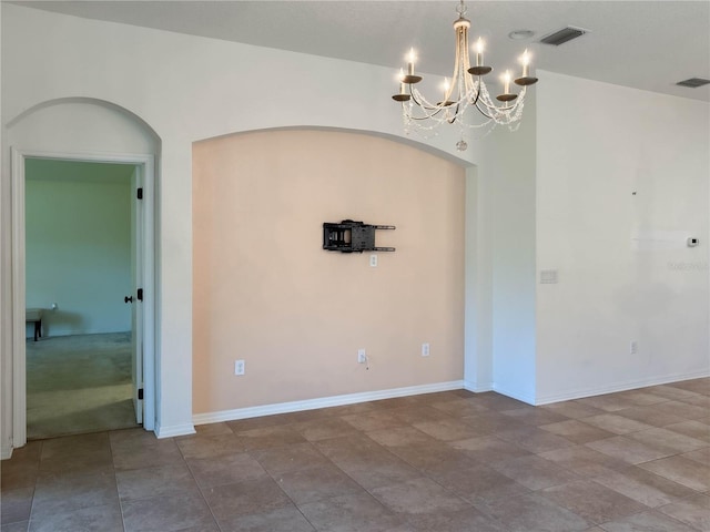 unfurnished room featuring arched walkways, baseboards, visible vents, and a notable chandelier