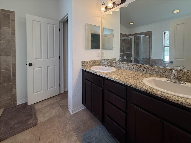 bathroom featuring double vanity, a stall shower, a sink, and tile patterned floors