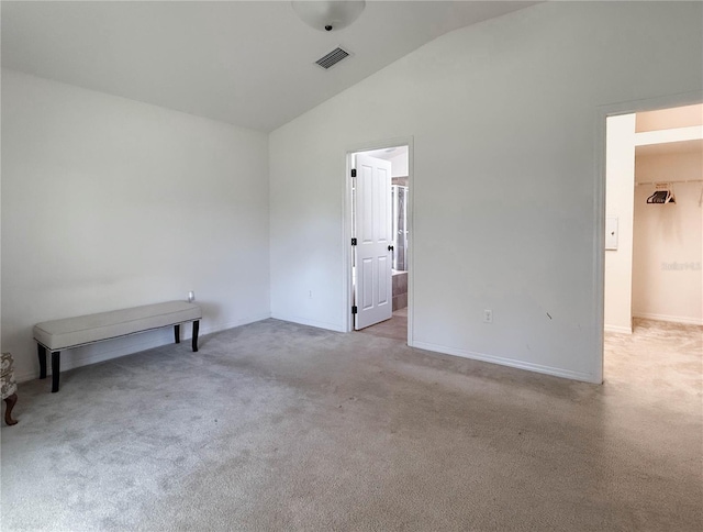 carpeted spare room featuring vaulted ceiling and visible vents