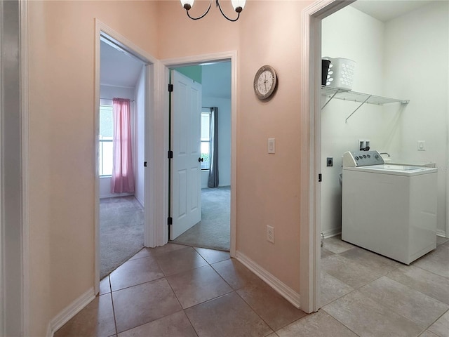 clothes washing area with laundry area, light tile patterned floors, baseboards, light colored carpet, and washer / clothes dryer