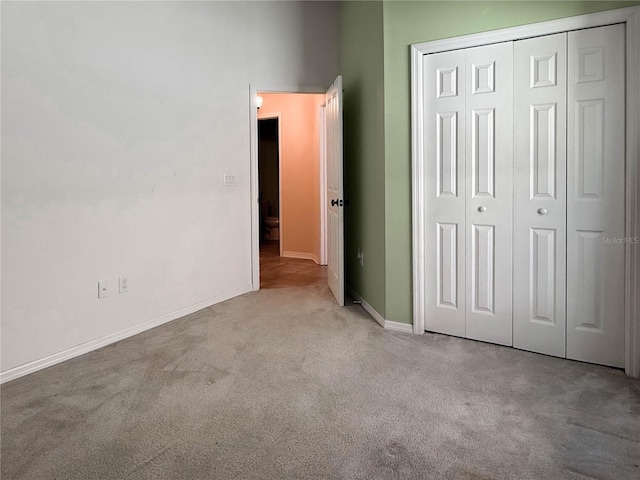 unfurnished bedroom with carpet floors, a closet, and baseboards