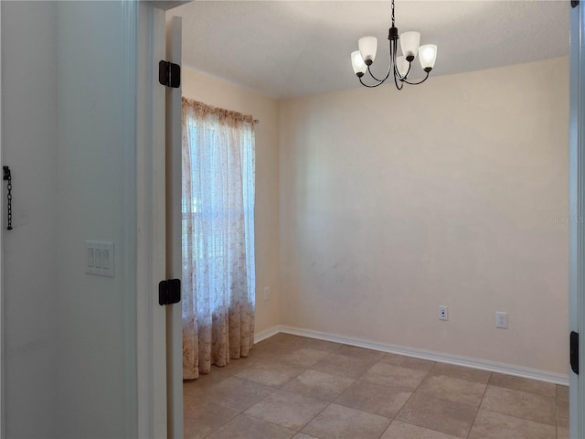 unfurnished room featuring a notable chandelier and baseboards