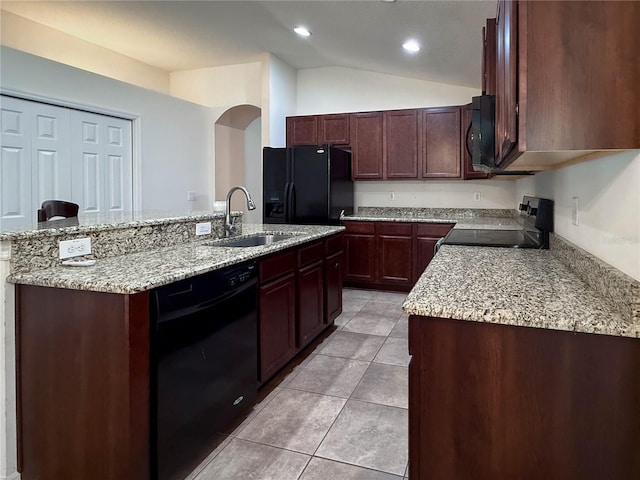 kitchen featuring lofted ceiling, light tile patterned flooring, a kitchen island with sink, a sink, and black appliances