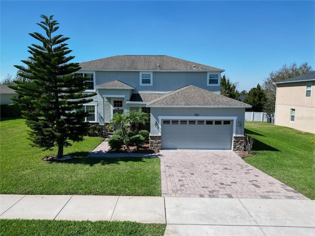 traditional-style house featuring a front lawn, decorative driveway, stone siding, and an attached garage