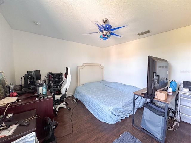 bedroom with a textured ceiling, wood finished floors, visible vents, and a ceiling fan