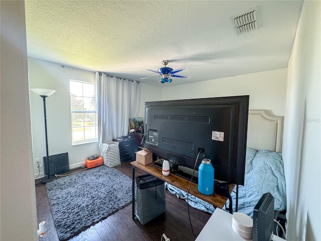 interior space featuring a textured ceiling, ceiling fan, wood finished floors, and visible vents