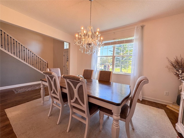 dining room featuring a textured ceiling, stairway, baseboards, and wood finished floors