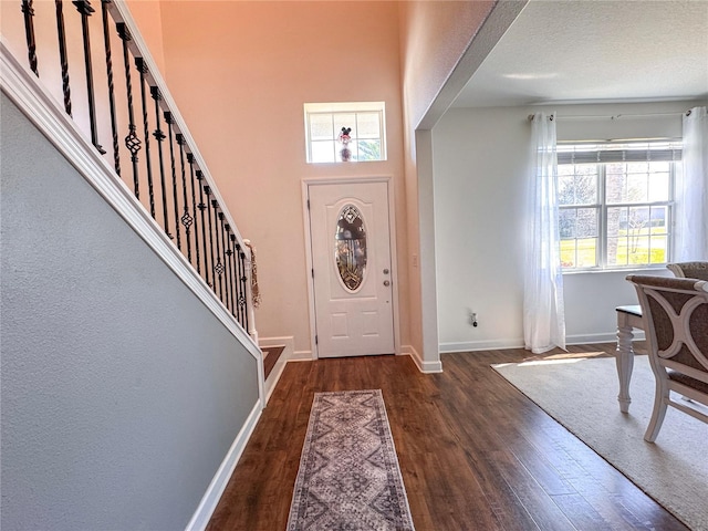 entryway with stairs, baseboards, and wood finished floors