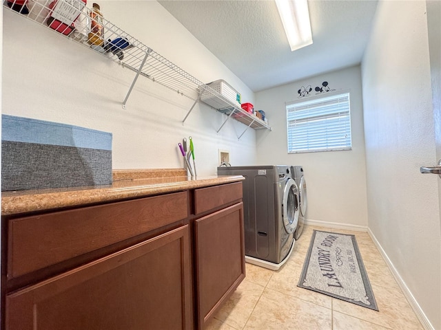 laundry room featuring light tile patterned floors, cabinet space, washing machine and dryer, a textured ceiling, and baseboards