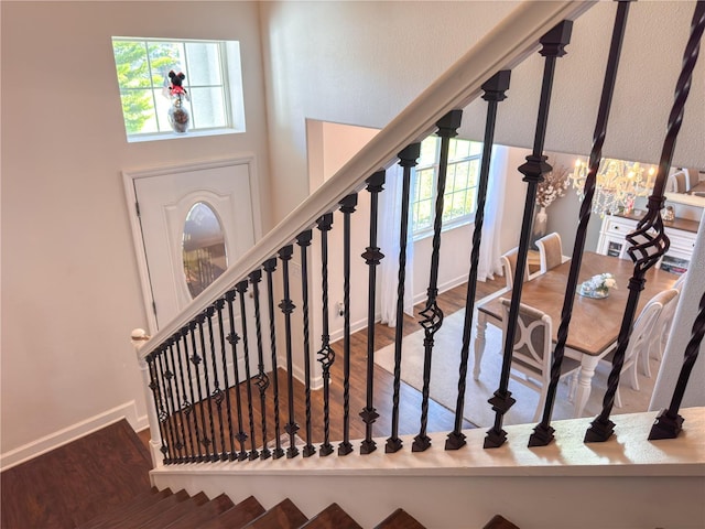 stairway featuring a high ceiling, baseboards, and wood finished floors