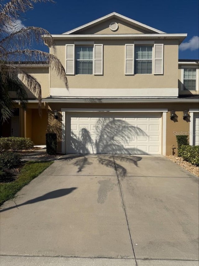 traditional-style house featuring concrete driveway, an attached garage, and stucco siding