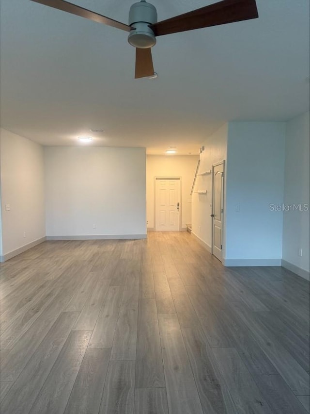 spare room featuring ceiling fan, baseboards, and wood finished floors