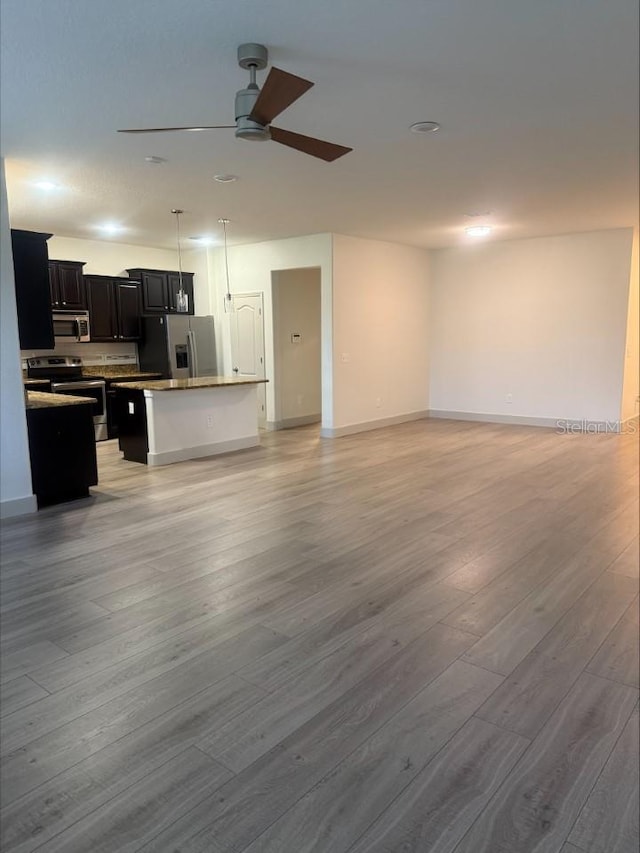 living room featuring ceiling fan, baseboards, and light wood-style flooring