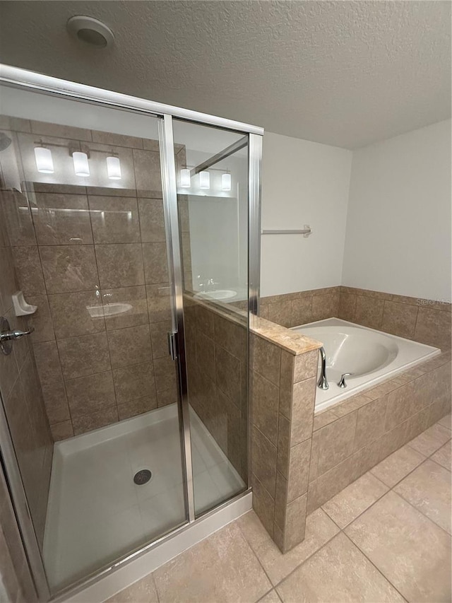 bathroom with a bath, tile patterned flooring, a shower stall, and a textured ceiling