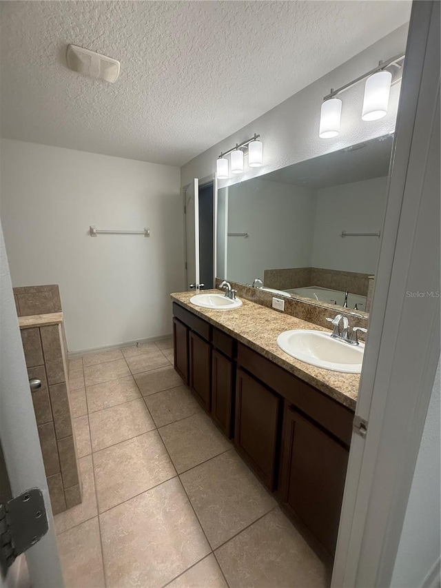 bathroom featuring a sink, a textured ceiling, double vanity, and tile patterned flooring