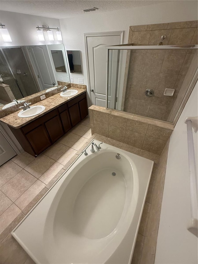 full bathroom featuring visible vents, a shower stall, a garden tub, a textured ceiling, and a sink