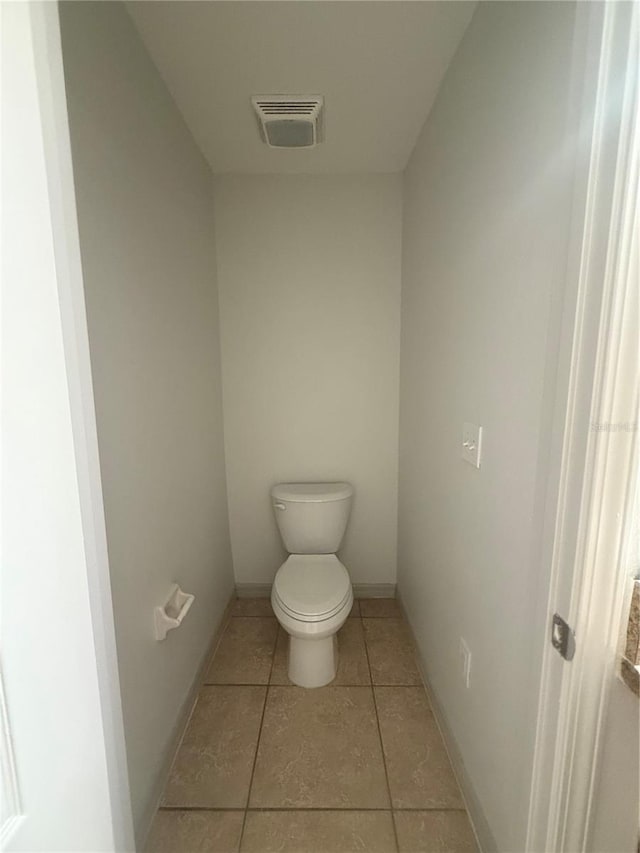 bathroom featuring tile patterned floors, visible vents, toilet, and baseboards