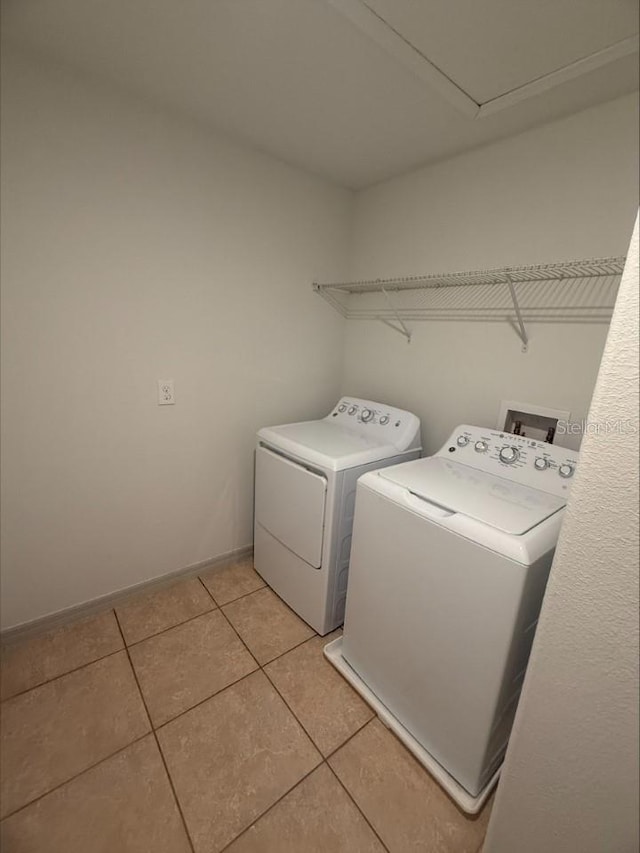 clothes washing area featuring washer and dryer, baseboards, laundry area, and light tile patterned floors