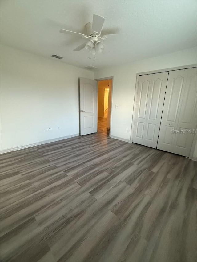 unfurnished bedroom featuring ceiling fan, wood finished floors, a closet, and baseboards