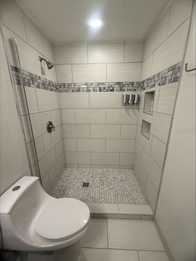 bathroom with tile patterned floors, toilet, and a shower stall