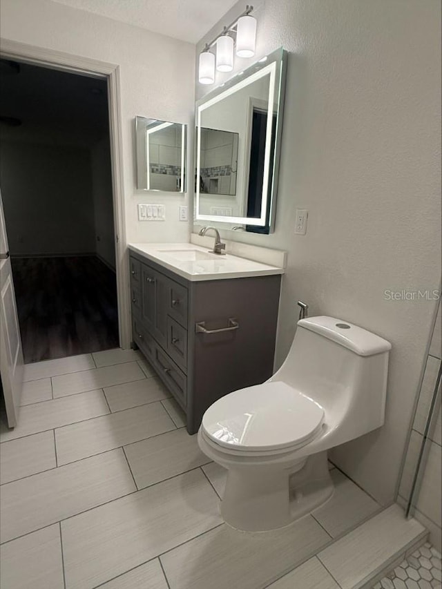 bathroom with toilet, vanity, and tile patterned flooring