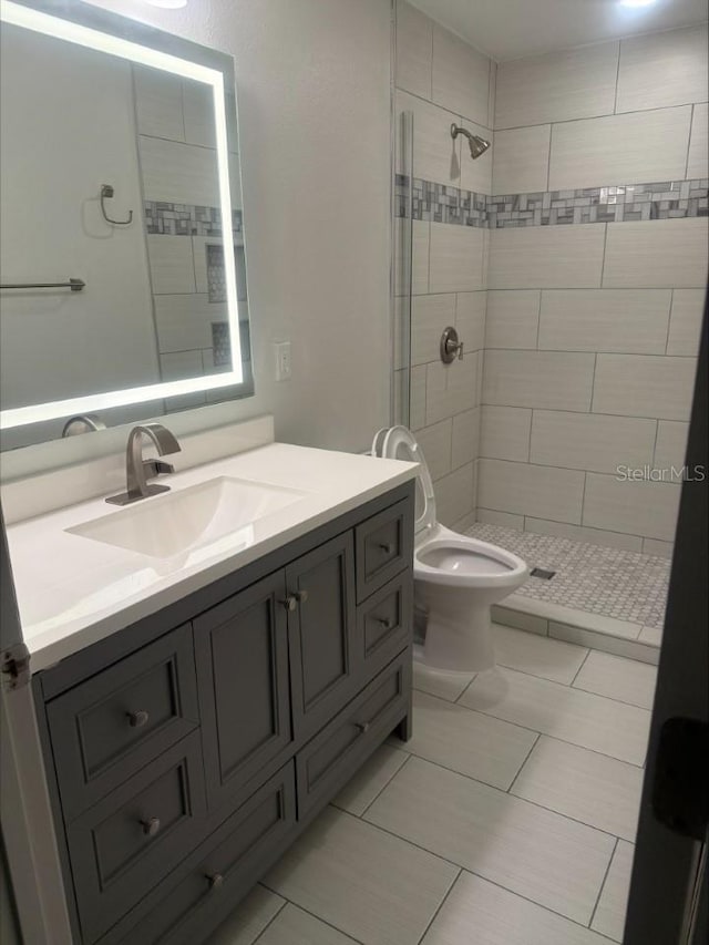 full bath featuring vanity, toilet, and a tile shower